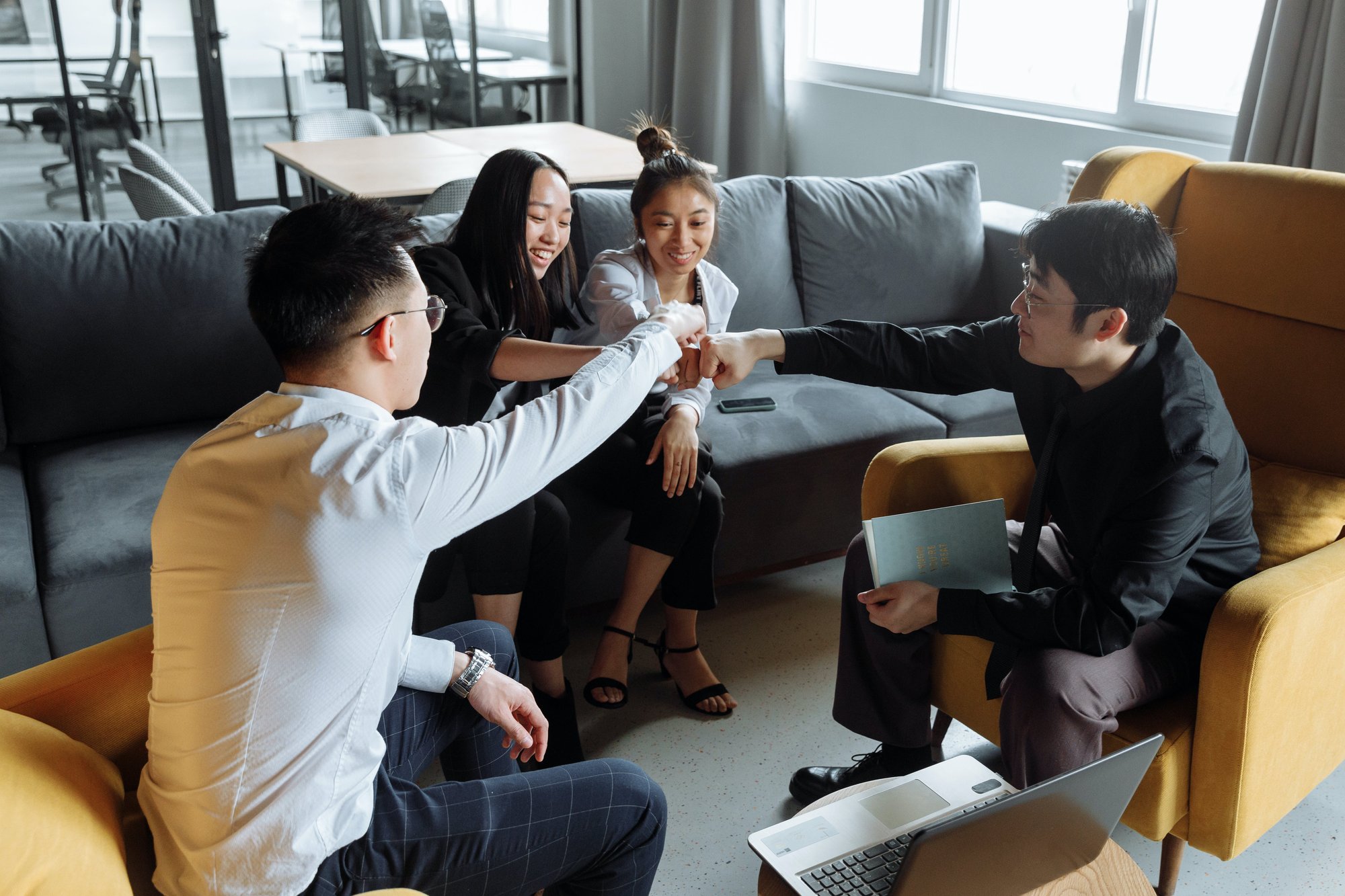 4 people celebrating work success with a fist bump